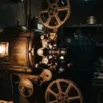 A detailed editorial photograph of a vintage cinema projector in a dimly lit projection booth
